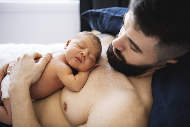 father lay on bed with his newborn baby daughter - Foto, Bild