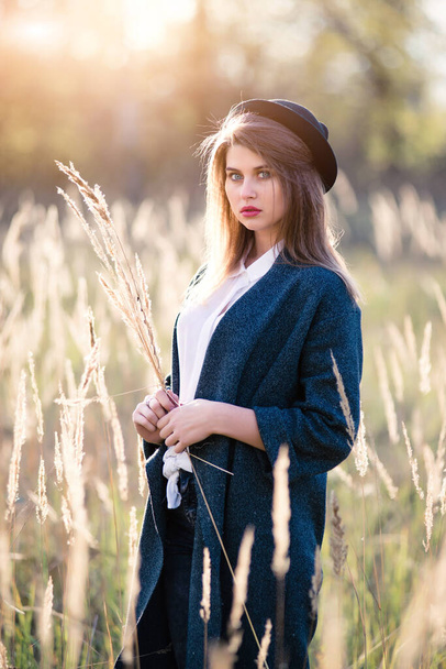 Beautiful woman in a hat and gray coat at sunset. Autumn mood. - Foto, Imagen