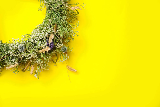 Beautiful wreath made of wildflowers on yellow background, top view. Space for text - Photo, Image