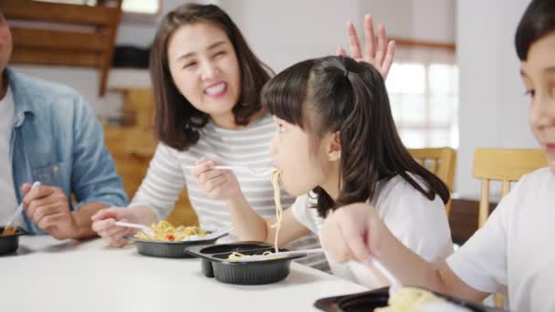 Heureuse famille asiatique joyeuse déjeuner manger des pâtes spaghetti dans un récipient en plastique dans la salle à manger à la maison moderne. Passer du temps ensemble, Auto-isolement, Distance sociale, Quarantaine pour le virus de la couronne. - Séquence, vidéo