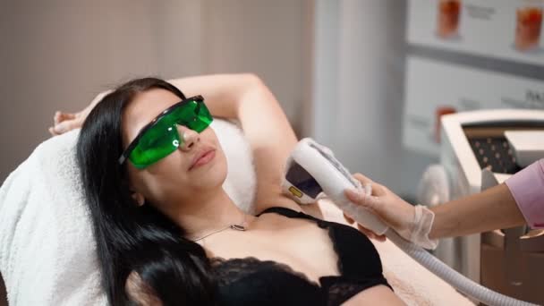 Nainen kosmetologi tekee kainalo laser karvojen poisto houkutteleva seksikäs nainen makaa lääketieteen sohvalla ja hymyilee kauneushoitola. Kosmitologia, epilataatio ja kylpylä käsite. Kehonhoito. Hidasta vauhtia. lähikuva - Materiaali, video