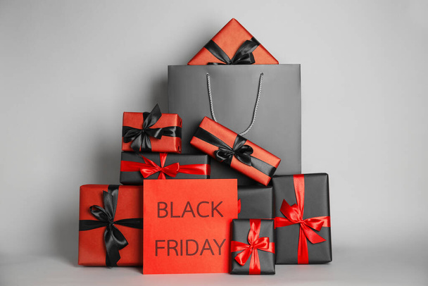Many gifts and sheet of paper with words Black Friday on light grey background - Foto, imagen