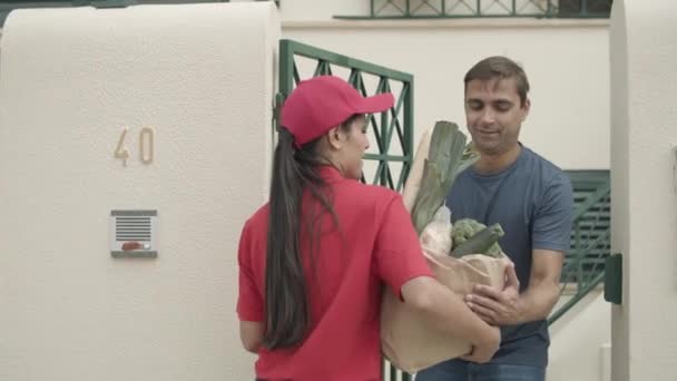Bastante mensajero chica en la tapa roja entrega de alimentos - Imágenes, Vídeo
