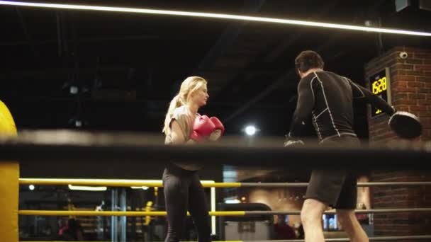 Przystojny trener uczy zdrową dziewczynę w klubie sportowym. Sport kobieta boks na siłowni - Materiał filmowy, wideo