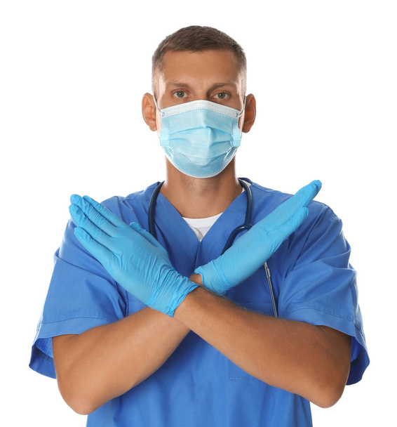 Doctor in protective mask showing stop gesture on white background. Prevent spreading of coronavirus - Fotografie, Obrázek