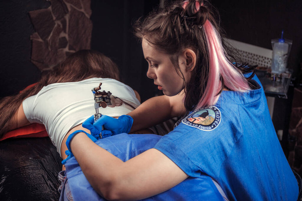 Professional tattoo artist makes a tattoo in a tattoo parlor - Photo, Image