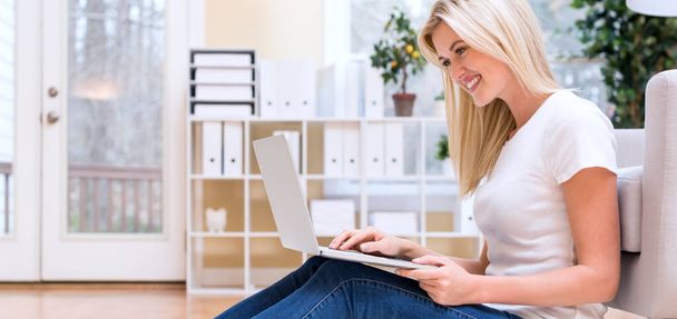 Happy young woman using her laptop - Photo, image