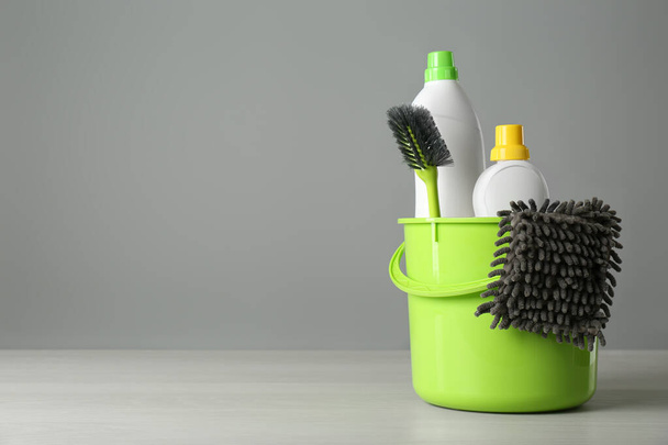 Bucket with cleaning products and tools on grey table. Space for text - Φωτογραφία, εικόνα
