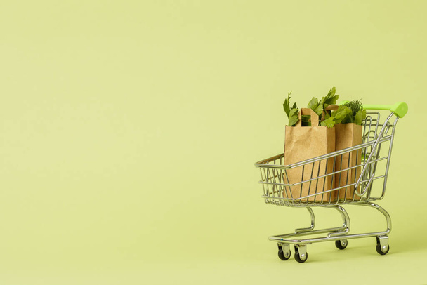 カート、トロリーで新鮮な緑のサラダと紙のショッピングバッグ。エコフードデリバリーコンセプト、菜食主義。健康管理。スペースのコピー - 写真・画像