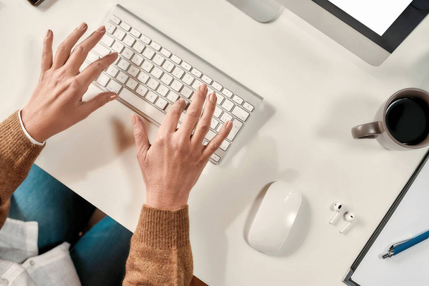 PCの前のテーブルに座ってキーボードを入力して白い成熟した女性の手のクローズアップ - 写真・画像