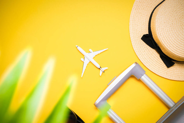 スーツケース、ヤシの葉とわらの帽子を持つサングラス、黄色の背景に旅行組成の白い飛行機。夏休みのコンセプトのデザイン - 写真・画像