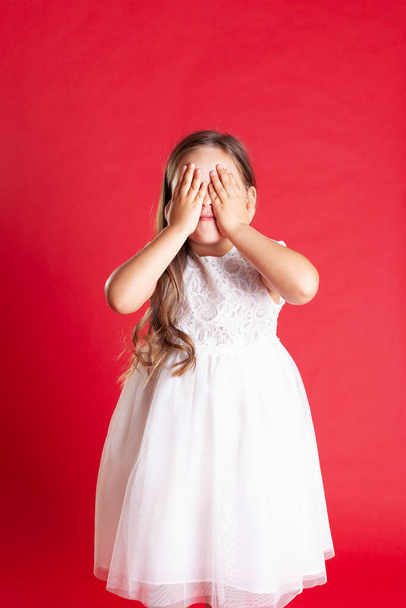 girl with wavy hair and white wedding dress covers her eyes with her hands waiting for a surprise or gift for Christmas  - Photo, Image