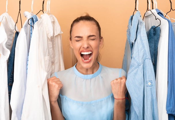 Πορτρέτο της συναισθηματικής γυναίκας ουρλιάζοντας στέκεται κοντά rack - Φωτογραφία, εικόνα