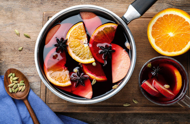 Delicious mulled wine and ingredients on wooden table, flat lay - Fotografie, Obrázek