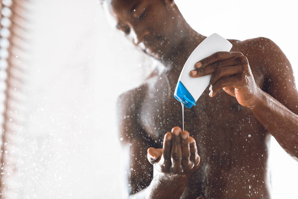 Black Man Pouring Shower Gel Washing Body In Modern Bathroom - Foto, immagini