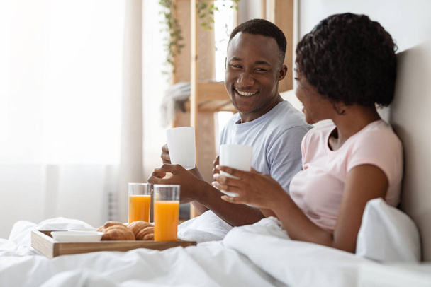 Onnellinen nuori musta pari syö aamiaista sängyssä aamulla - Valokuva, kuva
