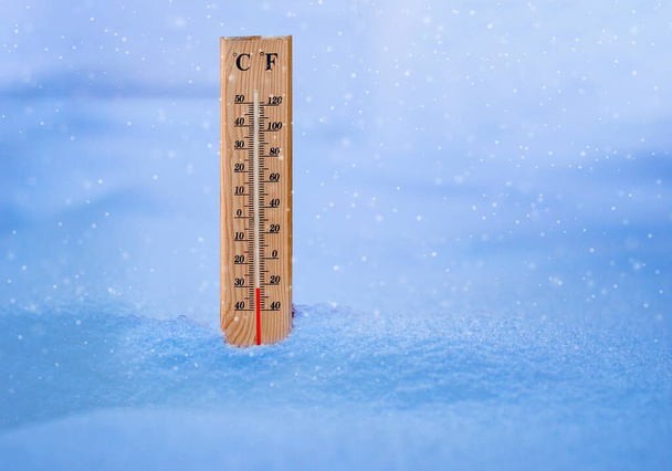 Kylmän lämpötilan mittaaminen puulämpömittarilla lumimyrskyn aikana. - Valokuva, kuva