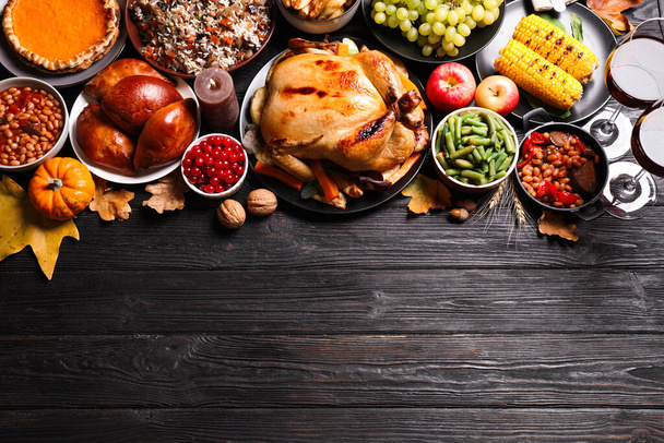 Traditional Thanksgiving day feast with delicious cooked turkey and other seasonal dishes on black wooden table, flat lay. Space for text - Fotó, kép
