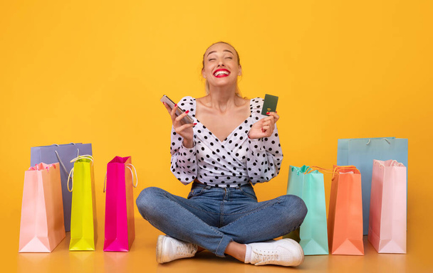 Mujer feliz sosteniendo el teléfono celular y la tarjeta de crédito - Foto, imagen