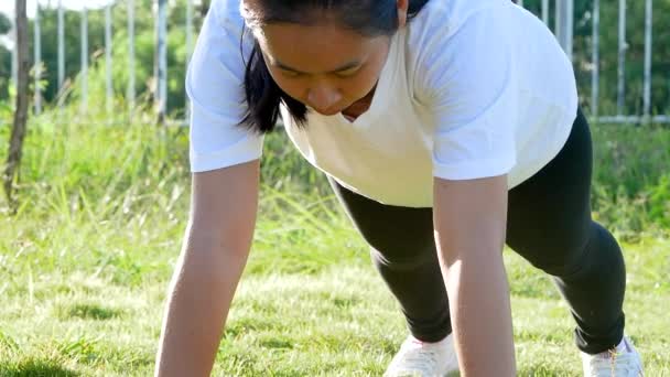 Retrato de una mujer joven que hace ejercicio al aire libre sintiéndose difícil flexiones de presión ejercicio con esfuerzo para bajar de peso. - Imágenes, Vídeo