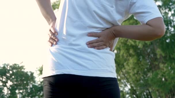 Close-up van jonge vrouw raakt haar rug letsel tijdens het sporten buiten. Gezondheidszorg en medische concepten. - Video