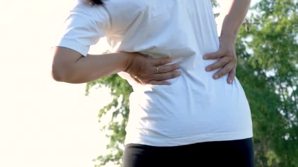 Nahaufnahme einer jungen Frau, die ihre Rückenverletzung beim Sport im Freien berührt. Gesundheitswesen und medizinische Konzepte. - Filmmaterial, Video