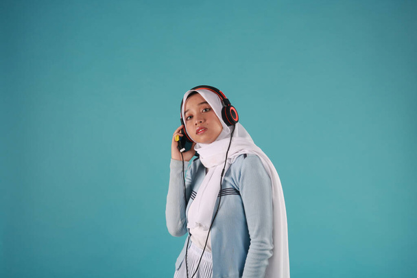 青い背景で音楽を聴く魅力的なアジアの女性。涼しい冬のコンセプト. - 写真・画像