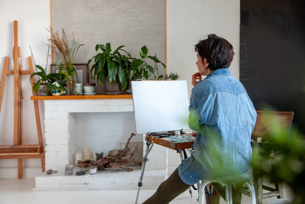 Συγκεντρωμένα κοντά μαλλιά γυναίκα καλλιτέχνης ζωγραφική σε βαμβακερό καμβά με ελαιογραφία στο σπίτι. Ζωγράφος - Φωτογραφία, εικόνα