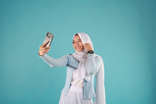 Portret Azjatki za pomocą smartfona na niebieskim tle. cool zimowa koncepcja. - Zdjęcie, obraz