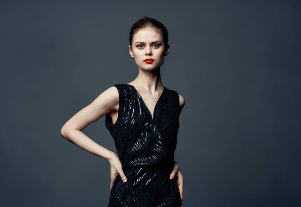 Charming lady in a black dress with bare shoulders on a gray background Copy Space - 写真・画像