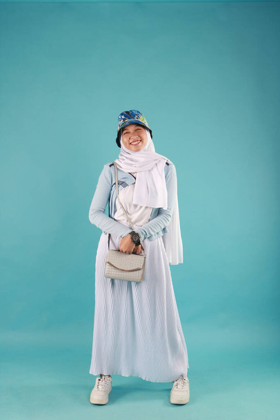 Модна фотографія красивої елегантної молодої азіатки, що тримає сумочку, позує на синьому фоні
. - Фото, зображення