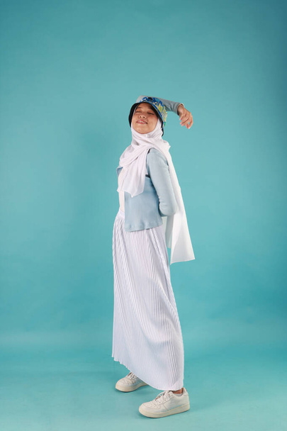 Fashion portrait of young beautiful asian muslim woman with wearing hijab on blue background - Valokuva, kuva