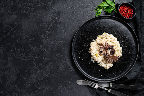 Risotto with octopus and mushrooms, parsley and spices. Black background. Top view. Space for text. - Foto, Imagem