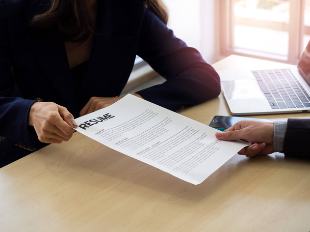Resume or CV paper. Applicant's hand in suit giving resume to employer for review the profile. Job interview and employment in office concept. - 写真・画像