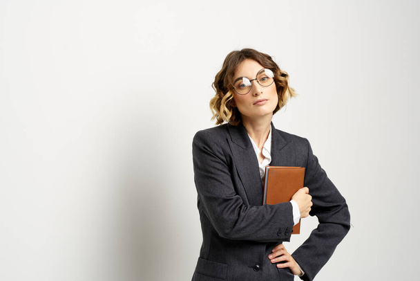 femme d'affaires dans un costume avec des documents dans les mains fond clair coiffure bouclée - Photo, image