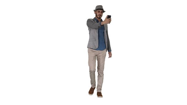 Arabský muž v ležérní oblečení chůze a tvorby selfie na bílém pozadí. - Fotografie, Obrázek