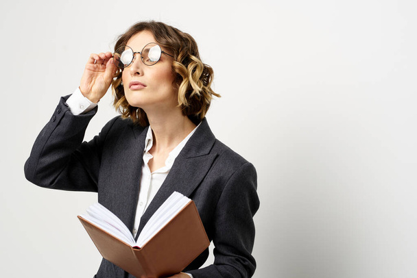 Mulher no trabalho com livro na mão luz fundo clássico terno óculos cabeça - Foto, Imagem
