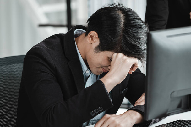 Stressed businessman worked with laptop computer and having a headache after business losses In the office room background. - Foto, immagini