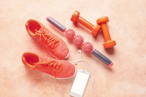 Ролик для тела с обувью, гантели и мобильный телефон на цветном фоне - Фото, изображение