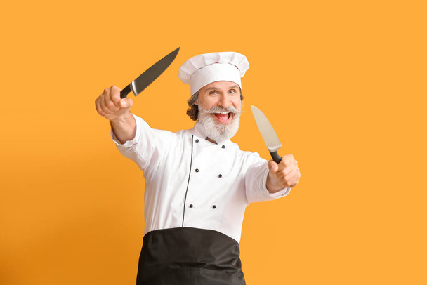 Starší samec kuchař s noži na barevném pozadí - Fotografie, Obrázek