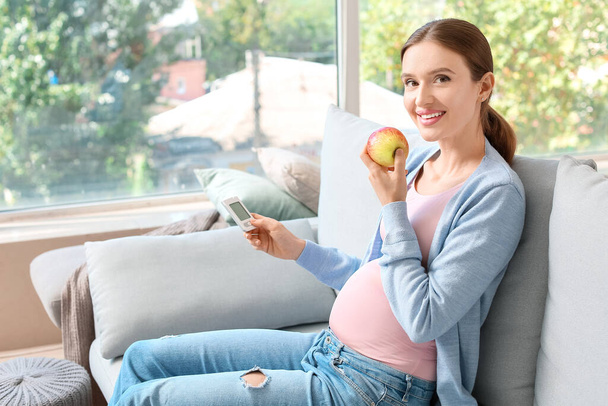 Mujer diabética embarazada midiendo el nivel de azúcar en la sangre en casa - Foto, Imagen