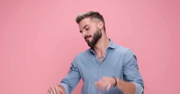 attractive casual man dancing around, pointing finger, gesturing call me, shooting with his finger gun against pink background - Záběry, video
