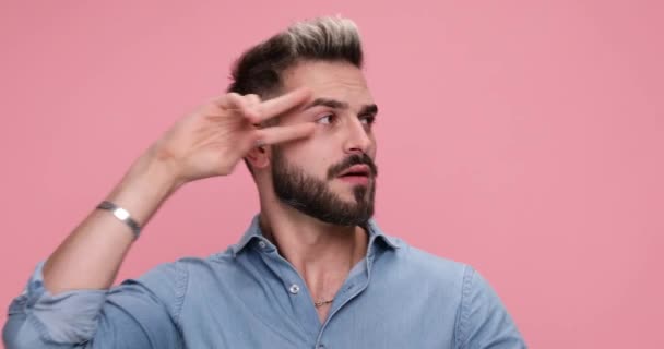 casual man dancing around and being carefree then switching to surprised, grumpy, anxious, slapping his face on pink background - Filmati, video
