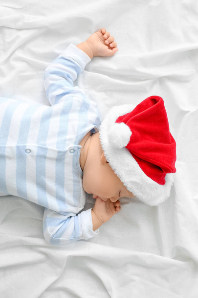 Cute little baby in Santa hat lying on bed - Fotoğraf, Görsel