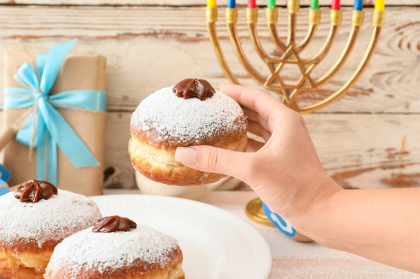 Woman eating tasty donut for Hanukkah - Photo, Image