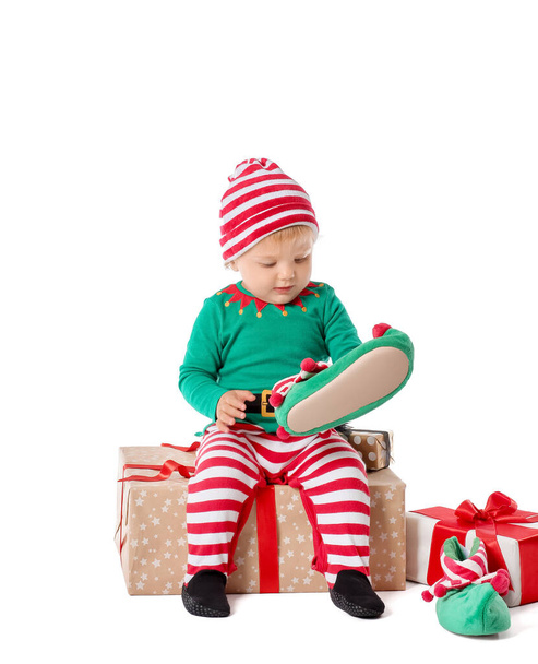 Cute little baby in elf's costume and with gifts on white background - Foto, afbeelding