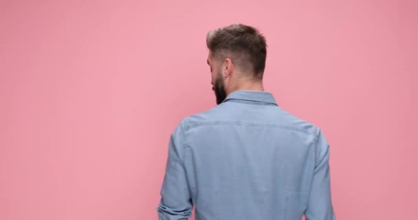сексуальный мужчина, стоящий на заднем плане, поворачиваясь, чувствуя удивление, указывая пальцем и показывая большой палец на розовом фоне - Кадры, видео