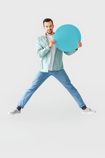 Jumping man with blank paper sheet on grey background - Foto, imagen