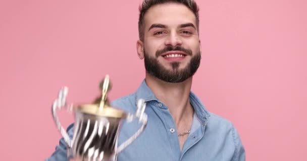 красивий випадковий чоловік піднімає свій трофей, вказуючи пальцем і даючи великий палець на рожевий фон
 - Кадри, відео