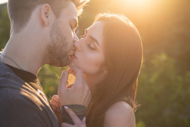 Sexy summer couple. Close-up of young romantic lovers is kissing. Profile of beautiful people in love expressing and affection while kiss each other with closed eyes on hot day. - Photo, Image